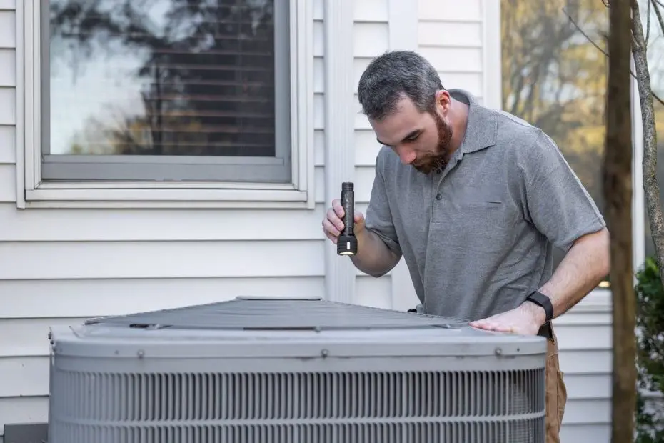 Technician with a flashlight inspecting an outdoor AC condenser, the work an HVAC marketing agency promotes