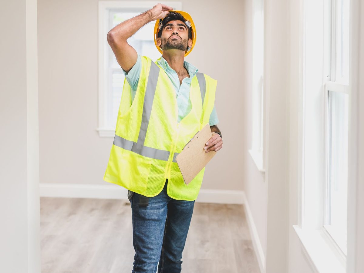 Contractor in a safety vest inspecting the interior of an empty home