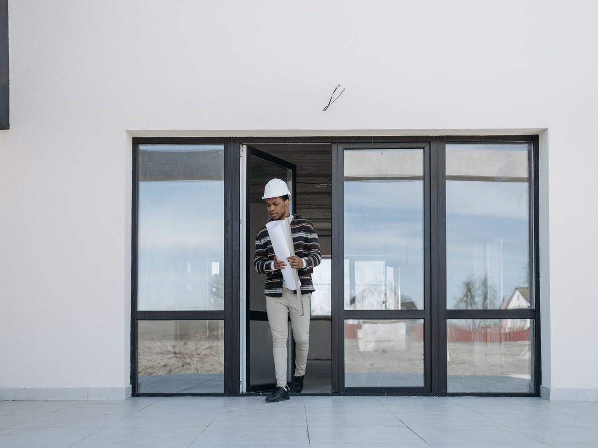 Contractor walking out of a new building while holding rolled construction plans