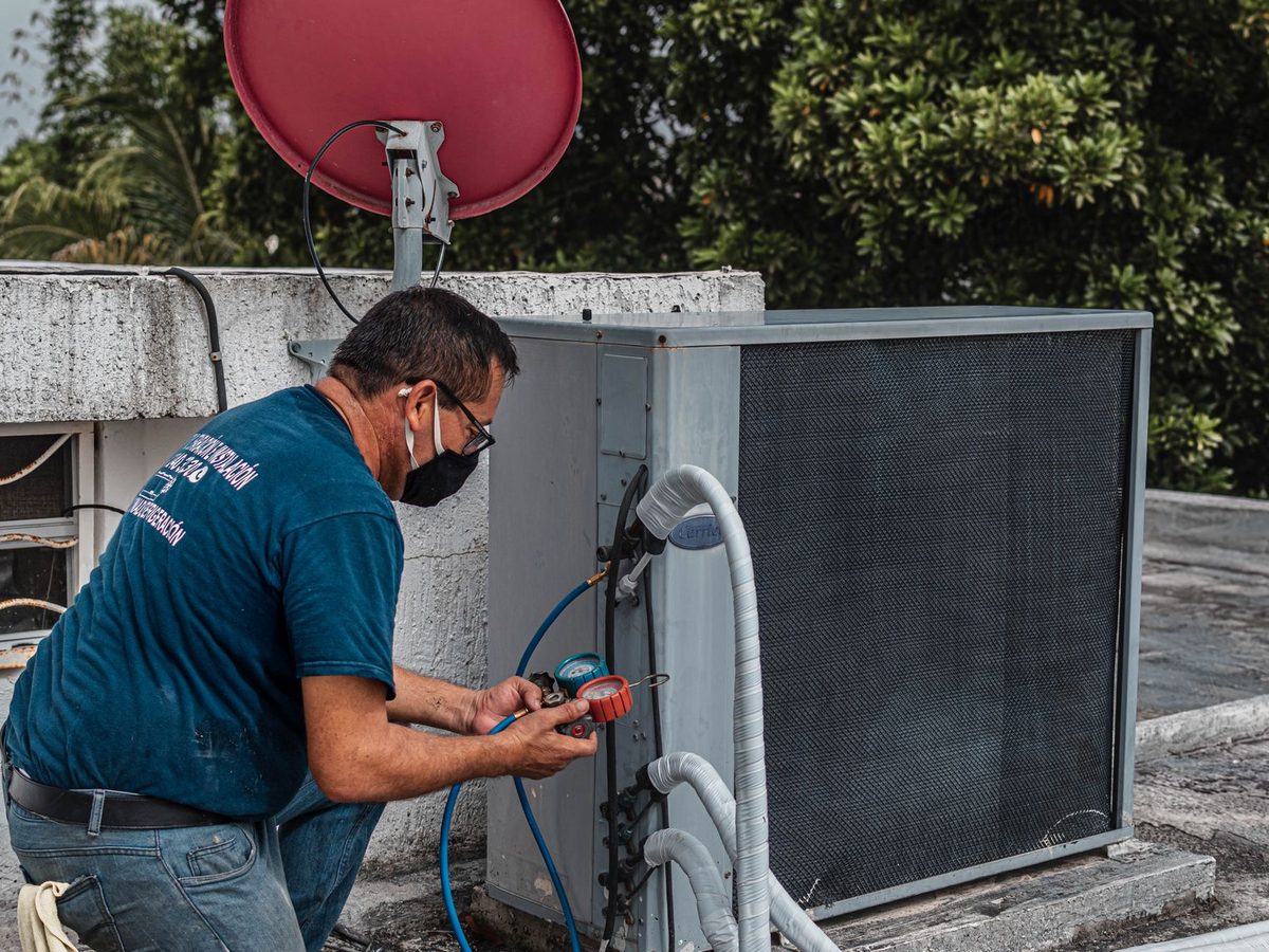 Technician with gauges servicing a rooftop air conditioning unit